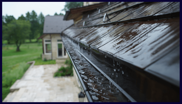 Rainwater overflowing from a gutter on a house roof.