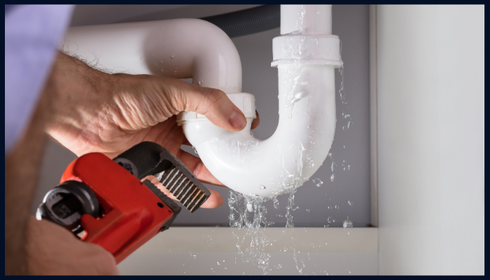 Plumber repairing a leaking pipe under sink during routine plumbing maintenance in Canberra.