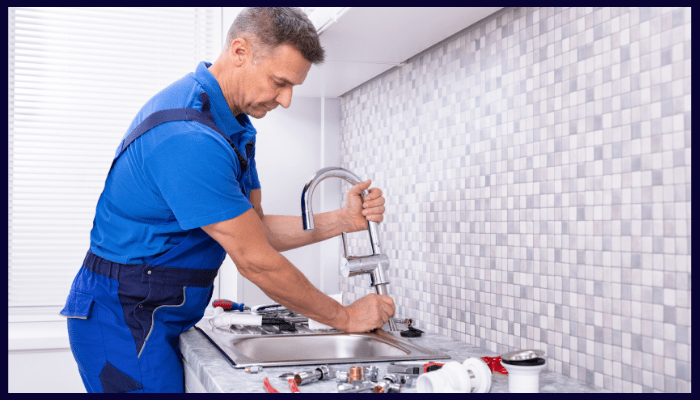 Plumber repairing a kitchen tap with tools on the counter — representing routine tap maintenance and leak prevention in Canberra homes.