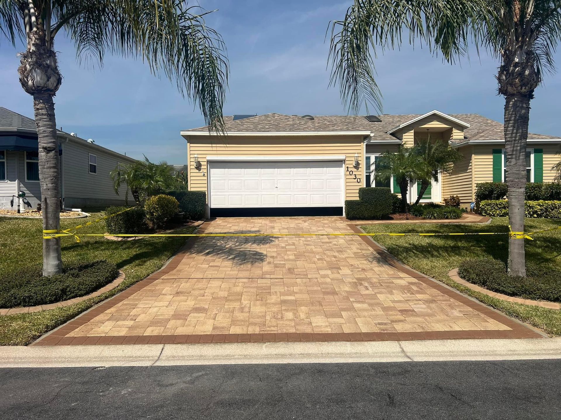 A brick driveway leading to a house with a garage door.