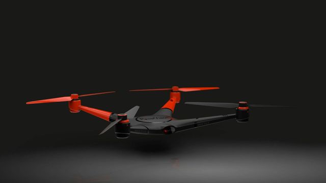 Drone with black body and red propellers against dark background.