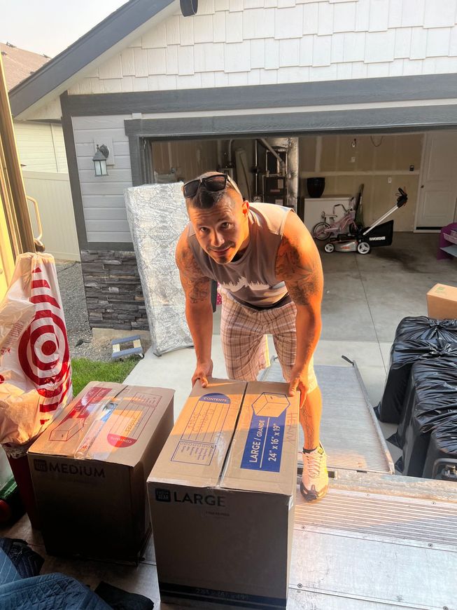 Man lifting a box with two others near a garage, moving day.