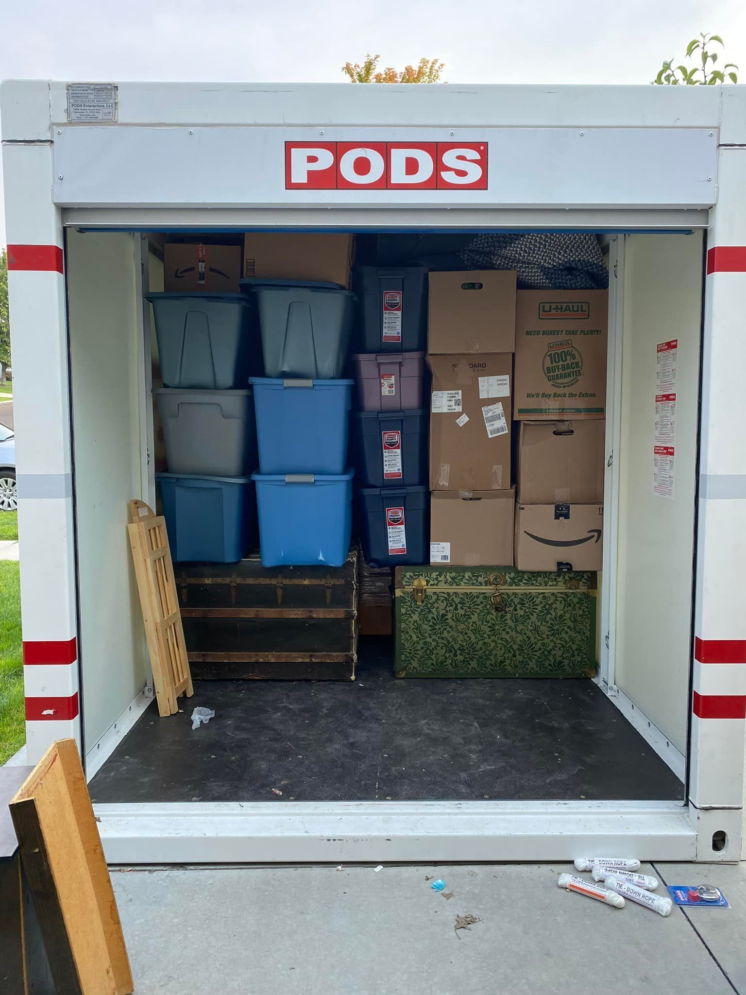 PODS storage container loaded with boxes and bins. Open doorway, white with red trim.