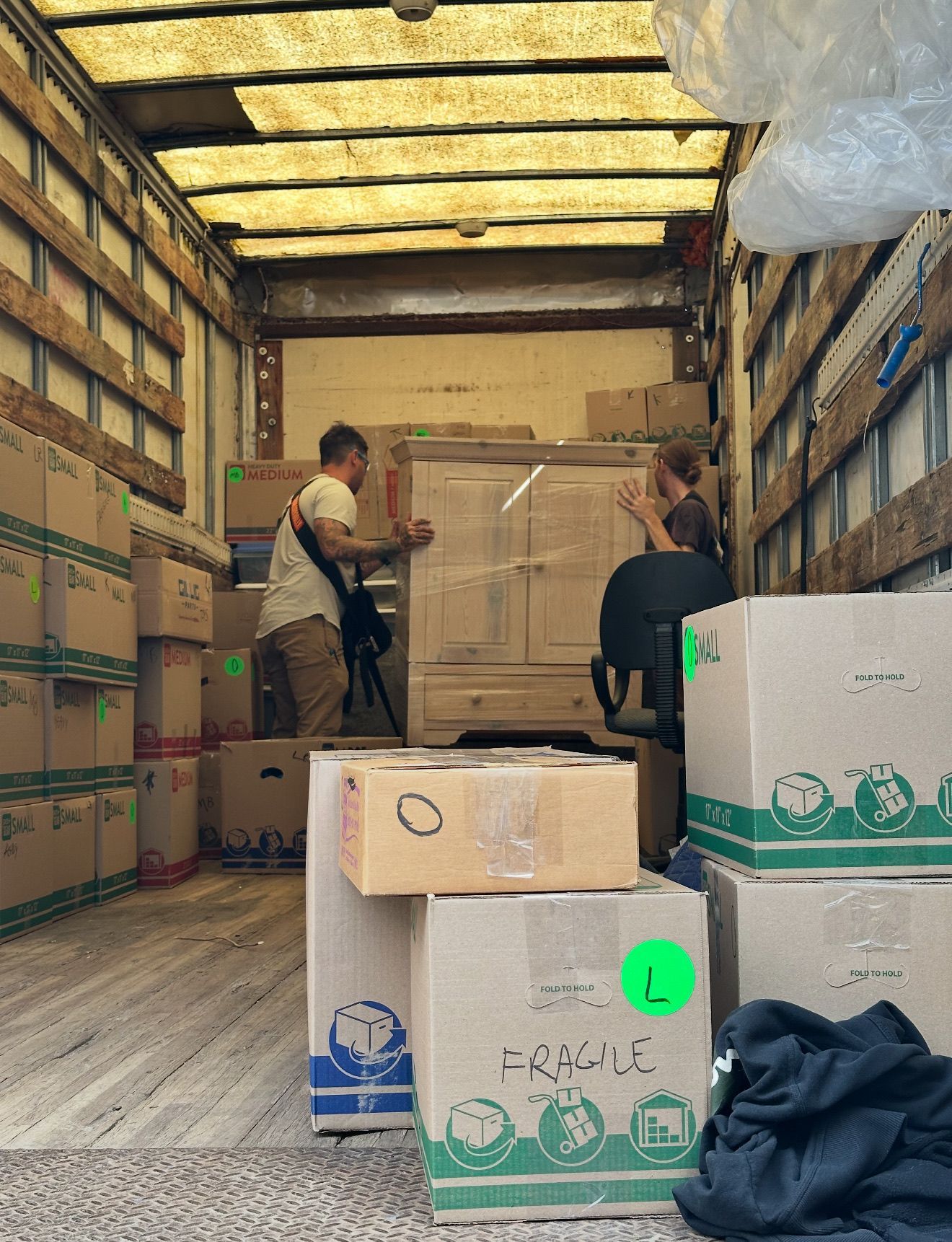 Two people loading furniture and boxes into a moving truck.