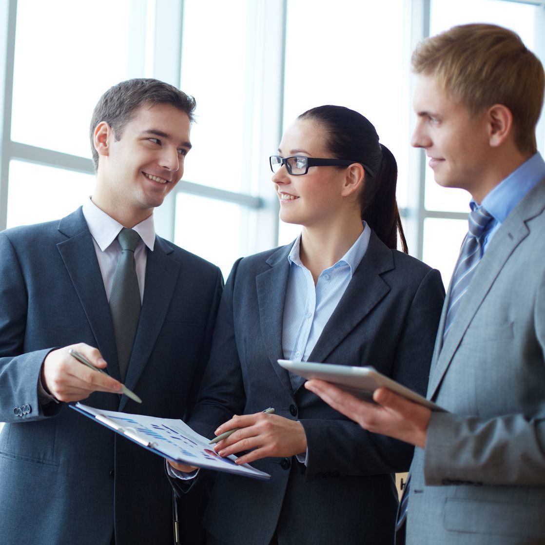 Three workers in suits holding tablets.