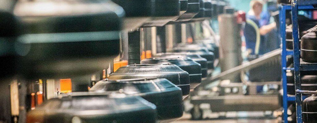 A line of black discs traveling on a conveyor in a factory.