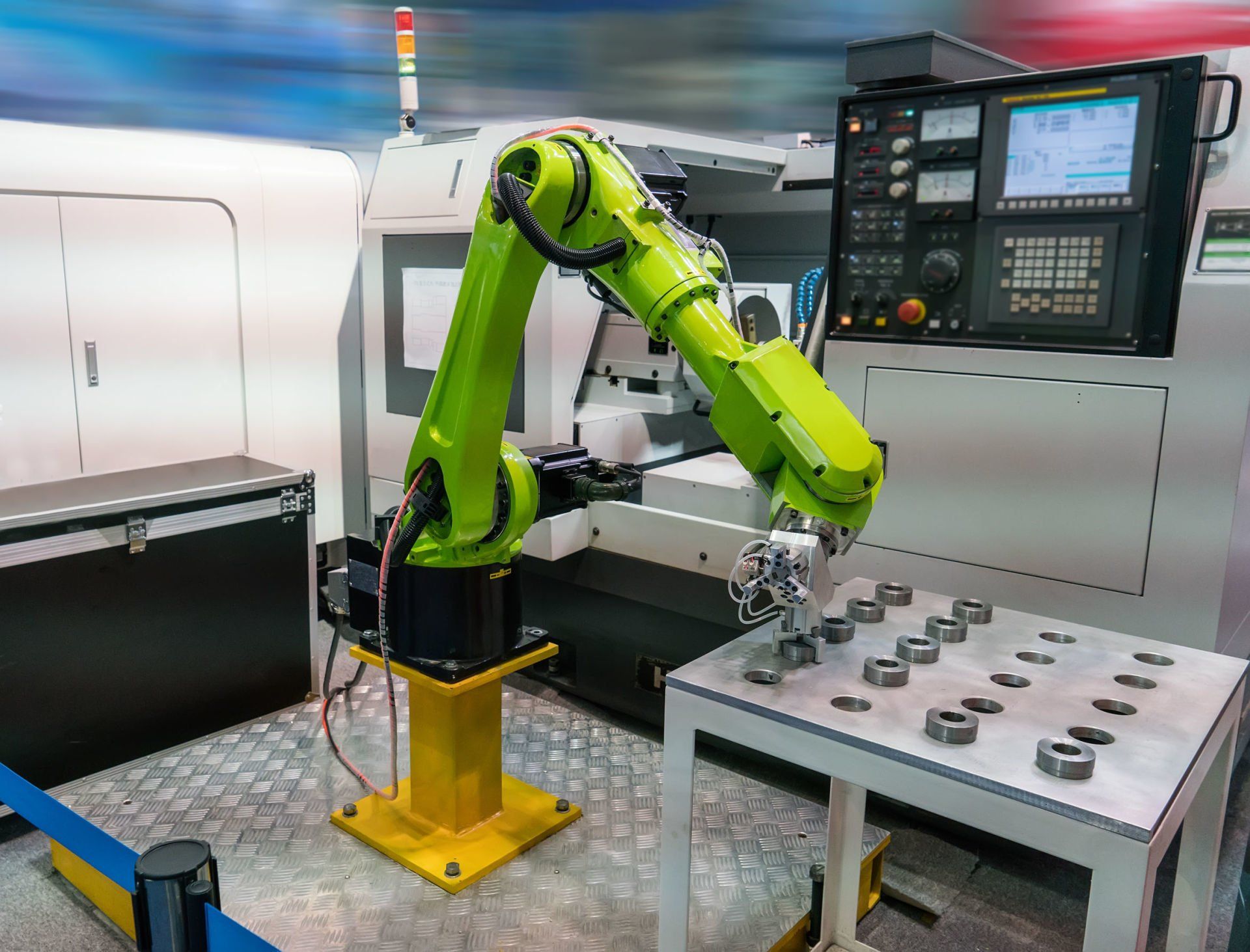 A green robotic arm robot positioning metal discs on a table