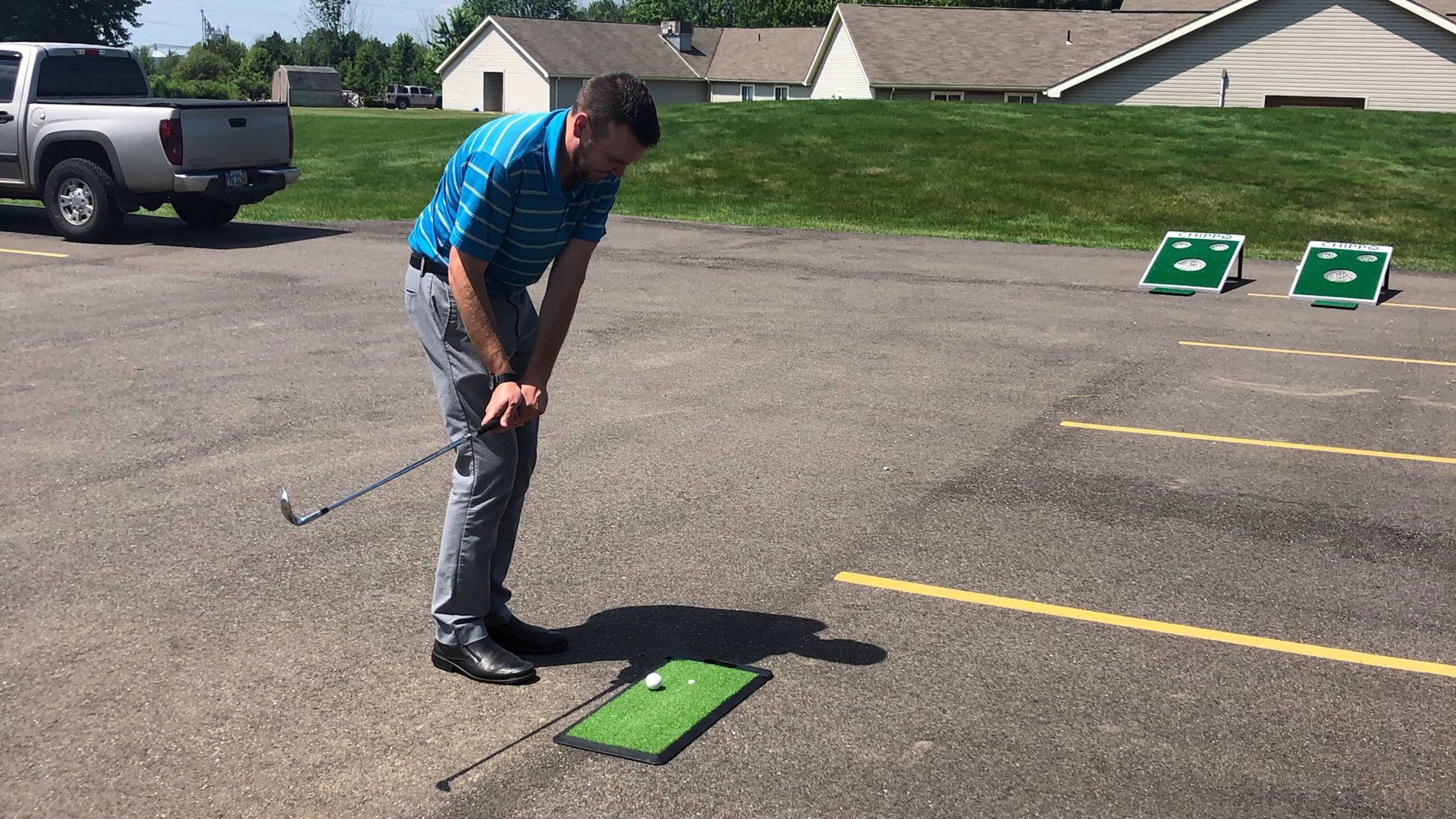 A man playing a cornhole golf game in a parking lot.