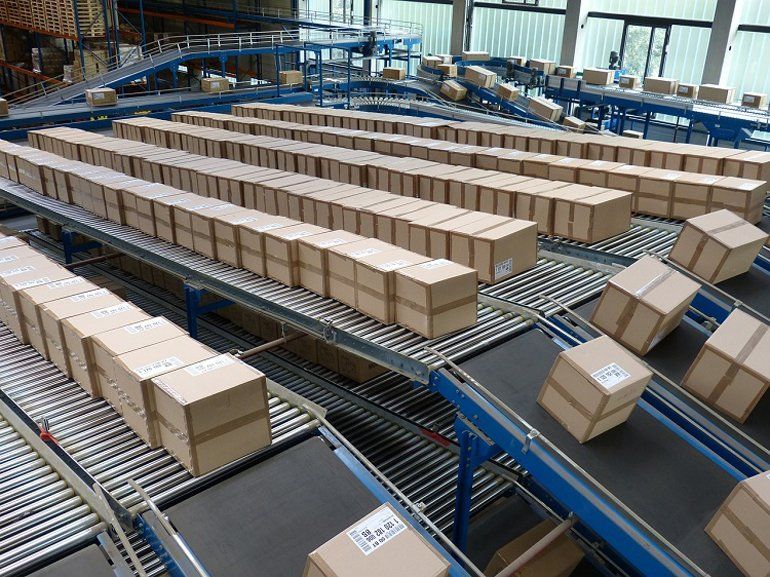 A row of conveyors with many cardboard boxes on top