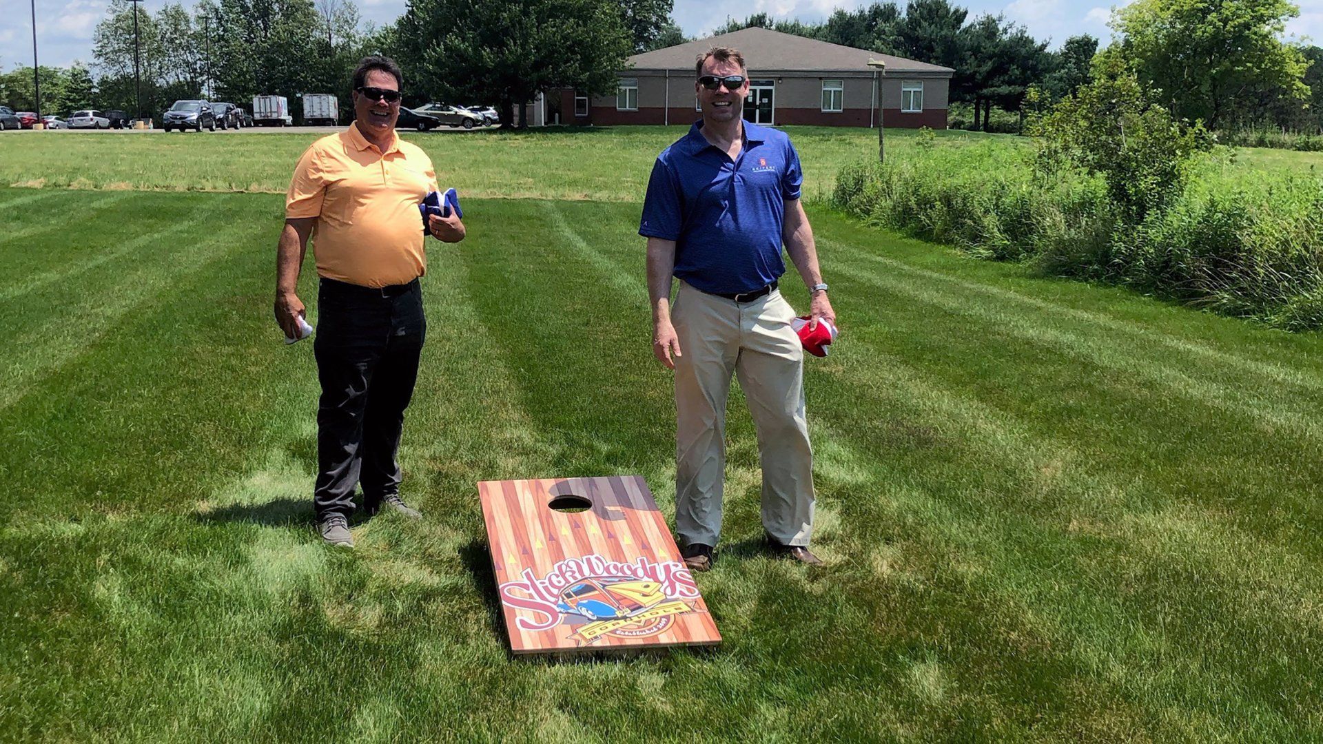 Two Seifert employees next to a cornhole board