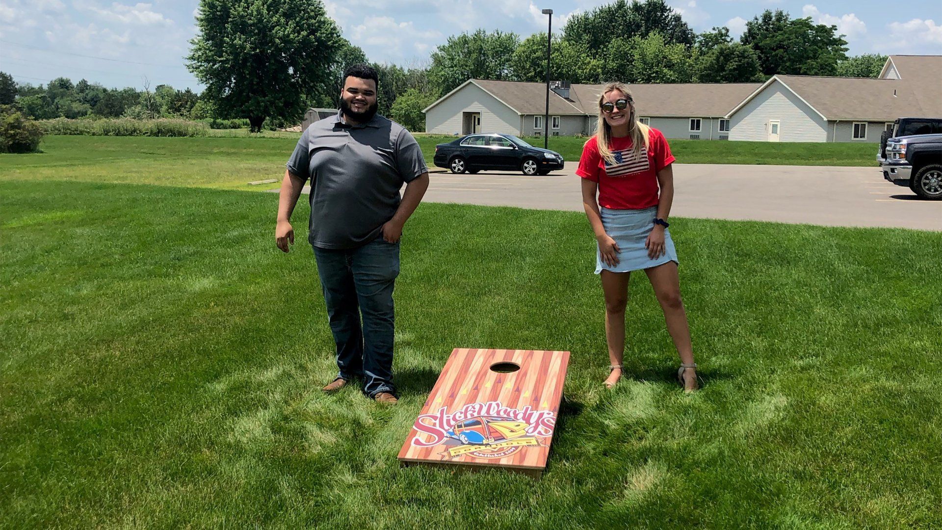 Two Seifert employees next to a cornhole board
