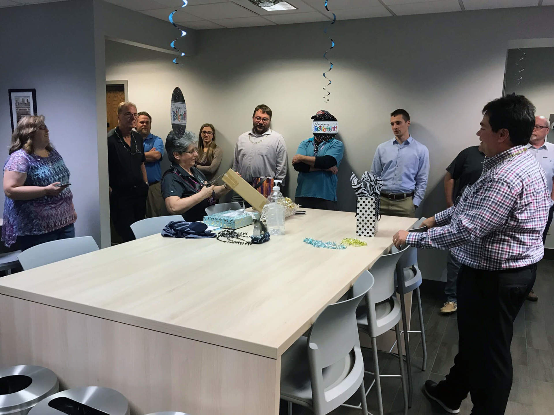 Grazyna opening a box on a table. Seifert employees are around her