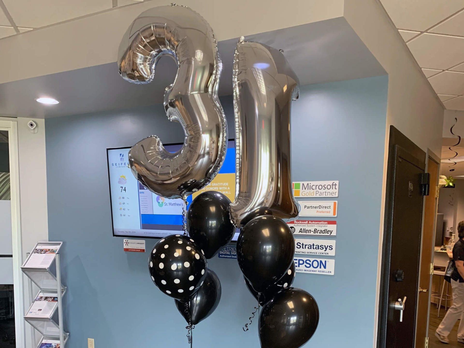 A few black balloons and two silver balloons in the shape of 