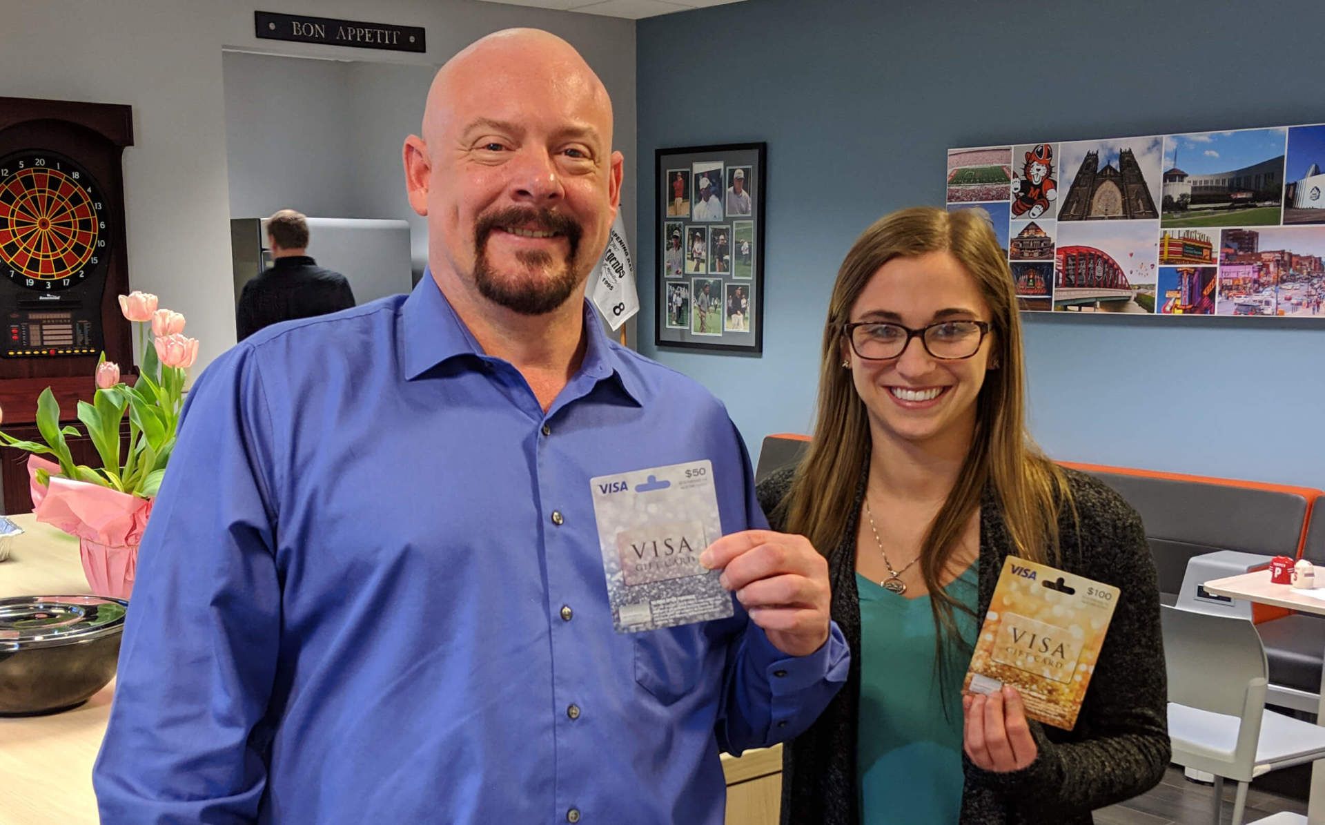 Two Seifert employees smiling and holding Visa gift cards.