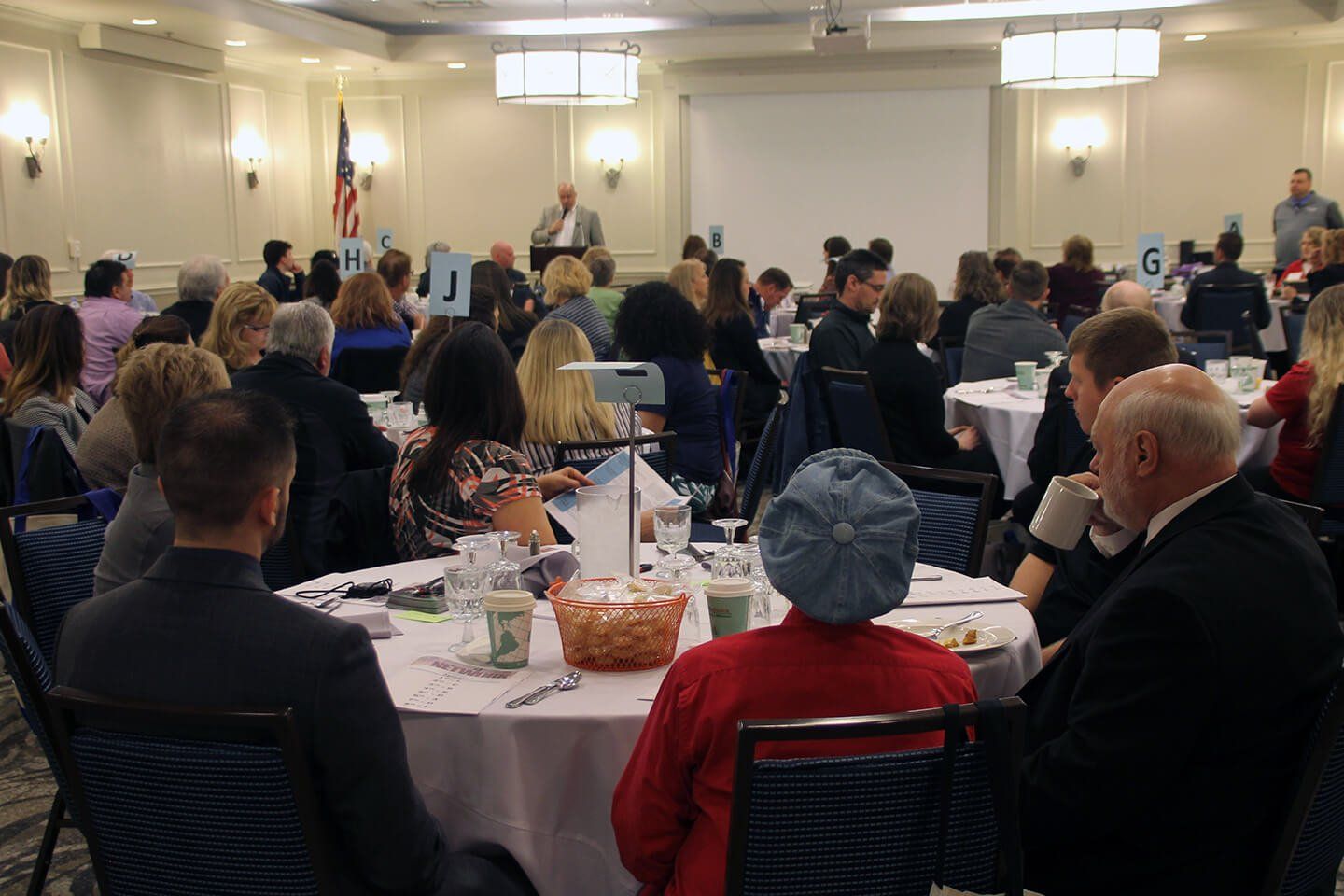 A filled convention room, with a presenter addressing the audience