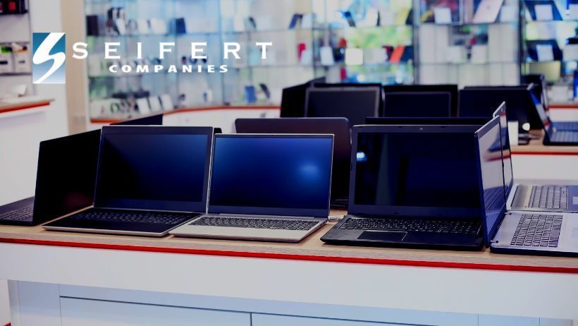 Several open laptops sitting on a desk. Laptops have black screens and appear off. Seifert logo top left.