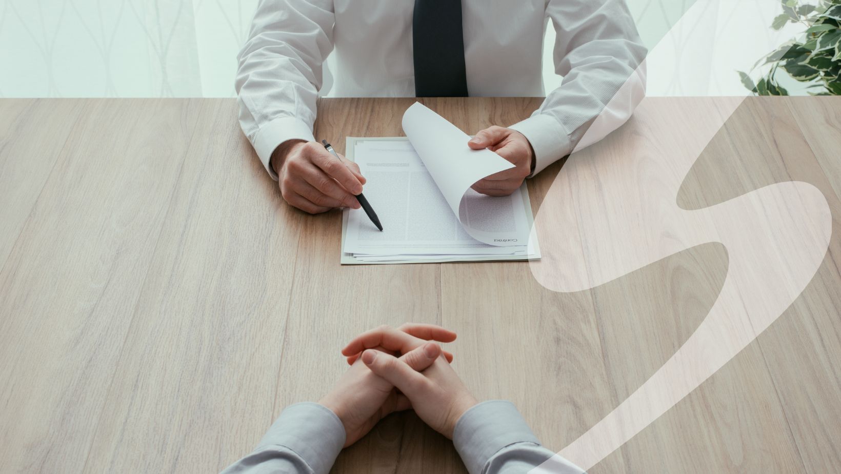 The viewer has their hands clasped and is being interviewed. The man across is pointing at text with a pen.