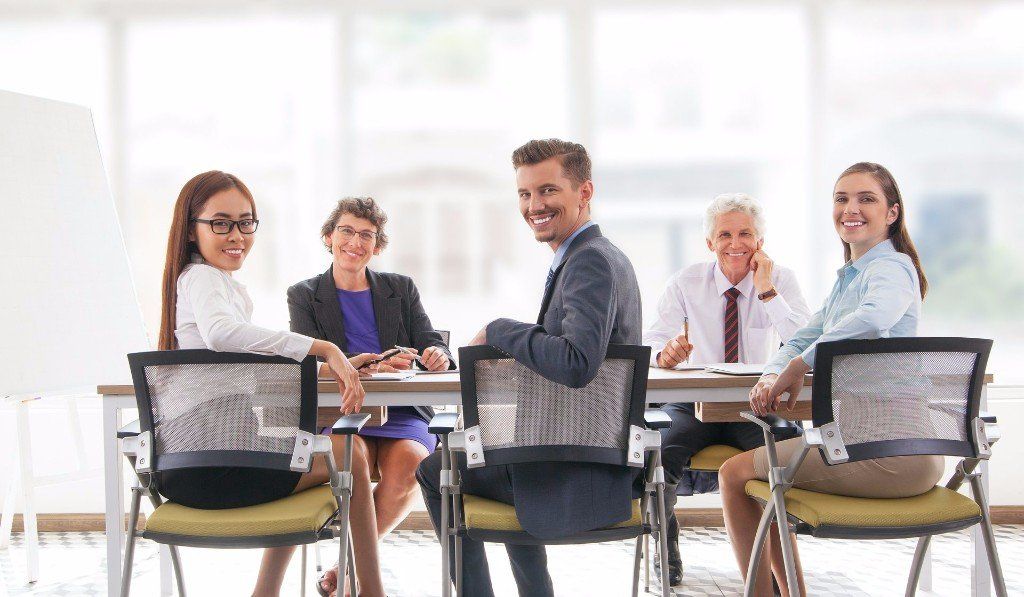 Five people at a table smiling