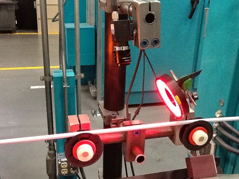 A white rod on some equipment, with a lamp with a red light shining upon it.