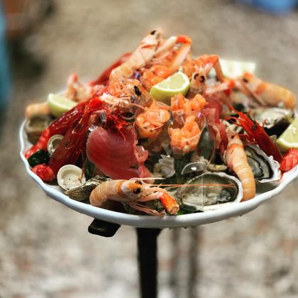 Piatto di frutti di mare con aragosta, gamberi, cozze e spicchi di lime su un piatto rialzato.
