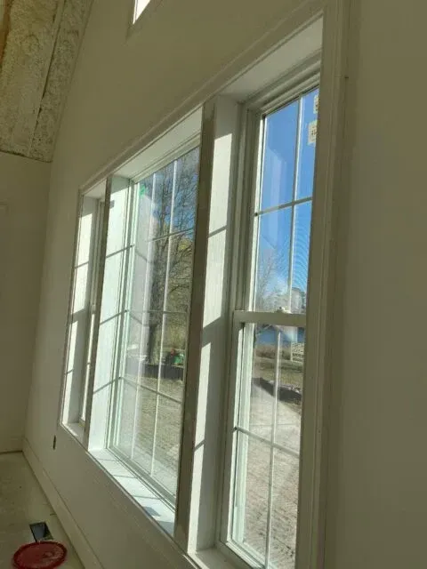 Woman in straw hat smiles, holding wine glass near a lake.