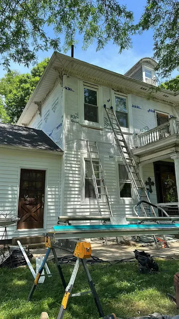 Woman in straw hat smiles, holding wine glass near a lake.