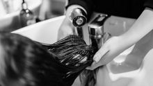 A woman is washing her hair in a sink at a hair salon.