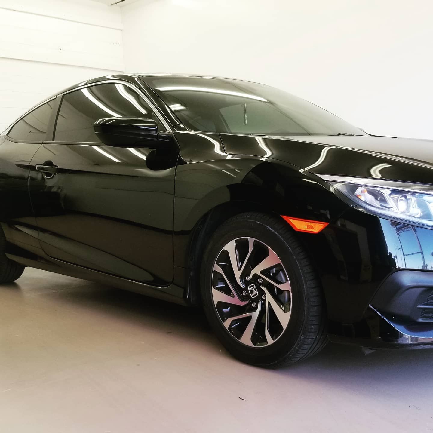 Black Honda Civic coupe parked in a brightly lit indoor space.