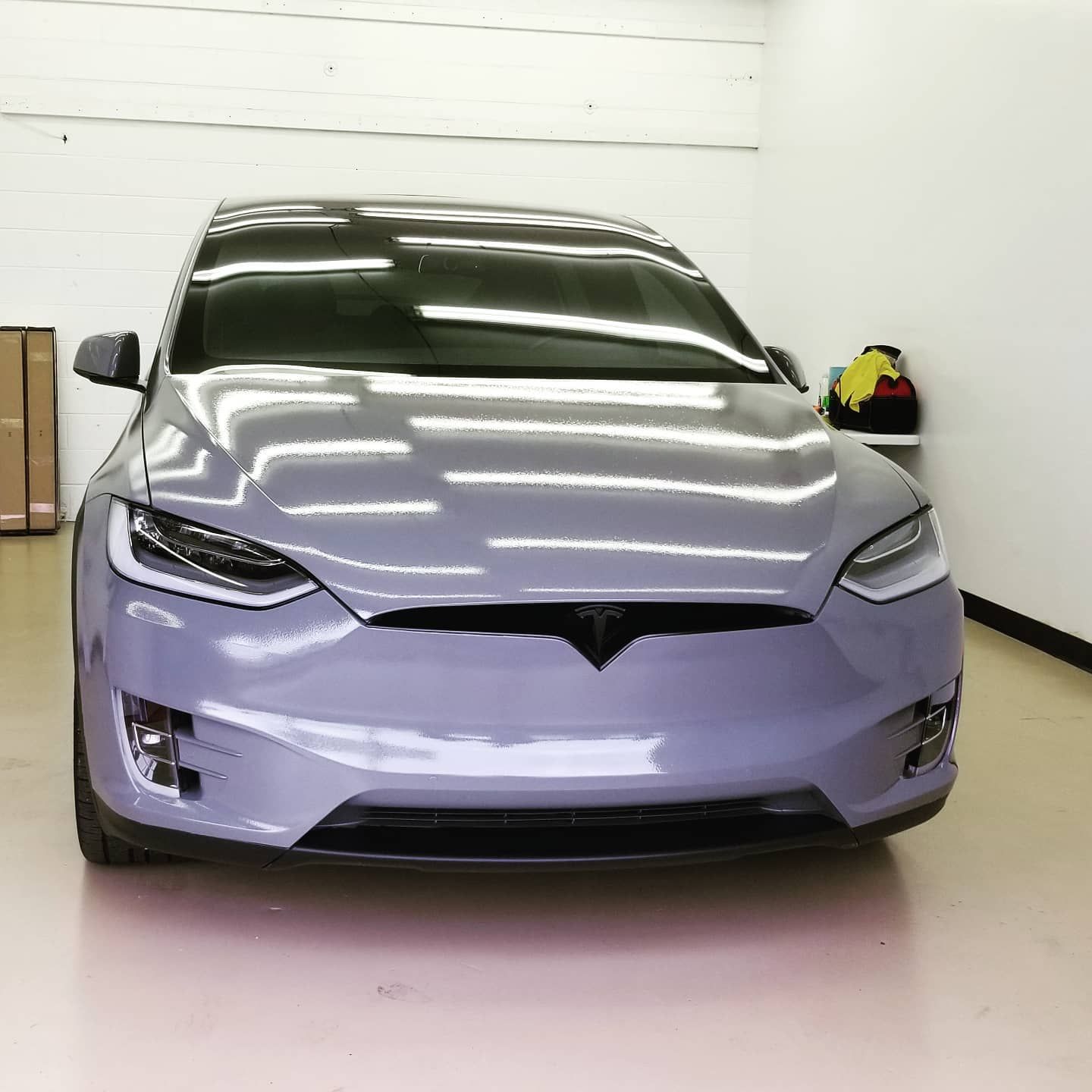 A gray Tesla Model X car parked inside a brightly lit garage.