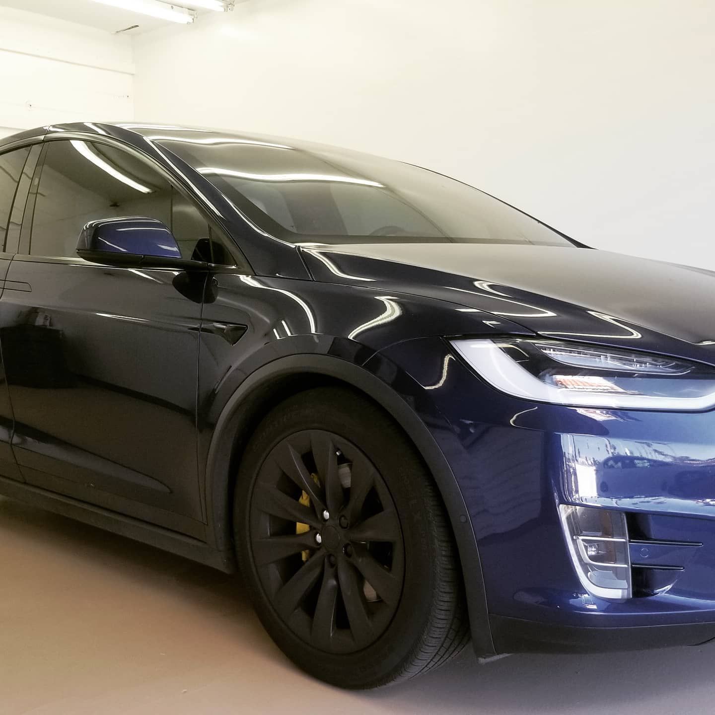 Dark blue Tesla Model X SUV parked indoors with black wheels.