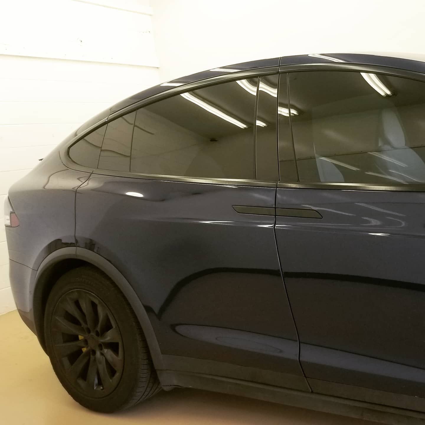 Blue Tesla Model X with tinted windows and black wheels parked indoors.