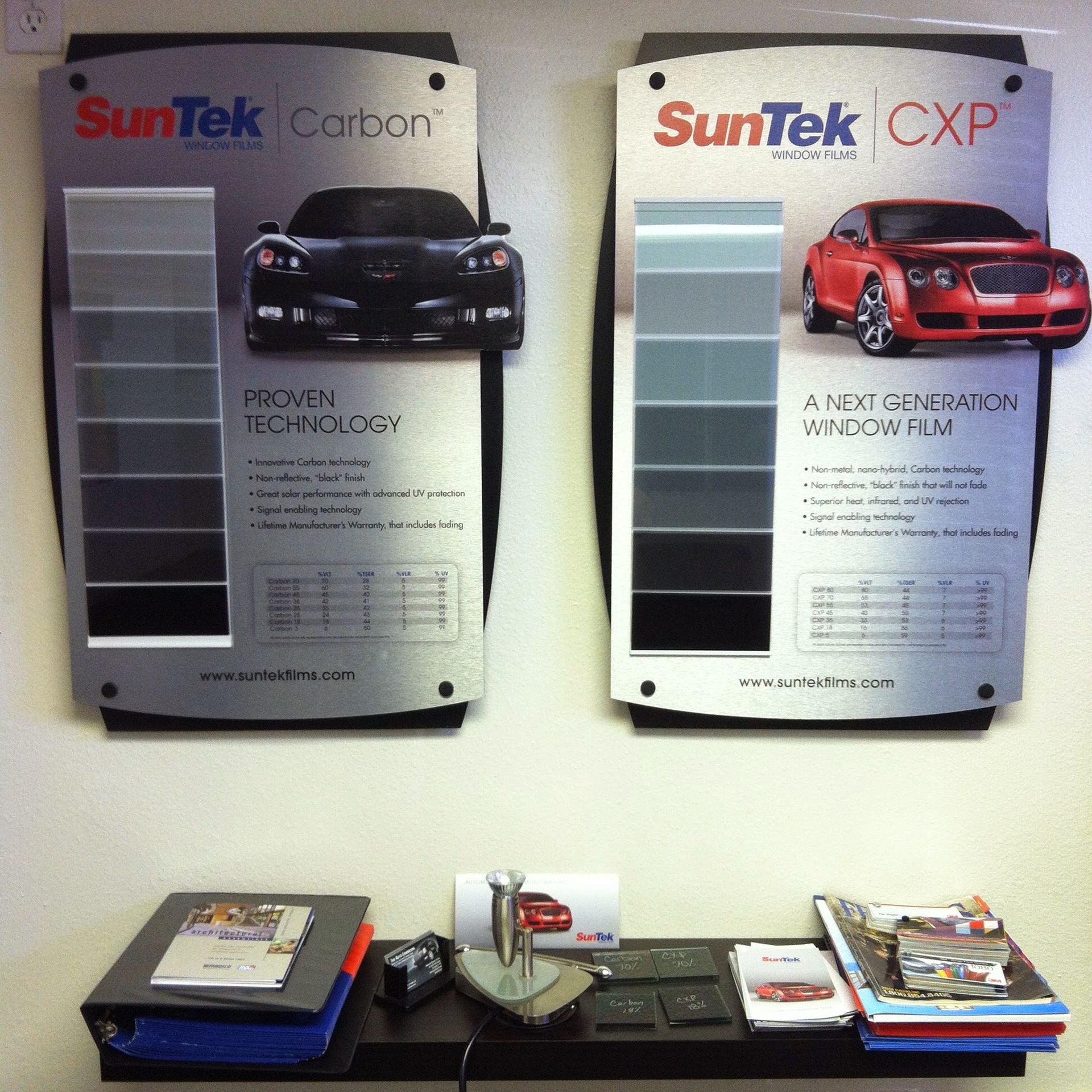 SunTek window tint display: two signs with cars and tint samples, shelf below with brochures.