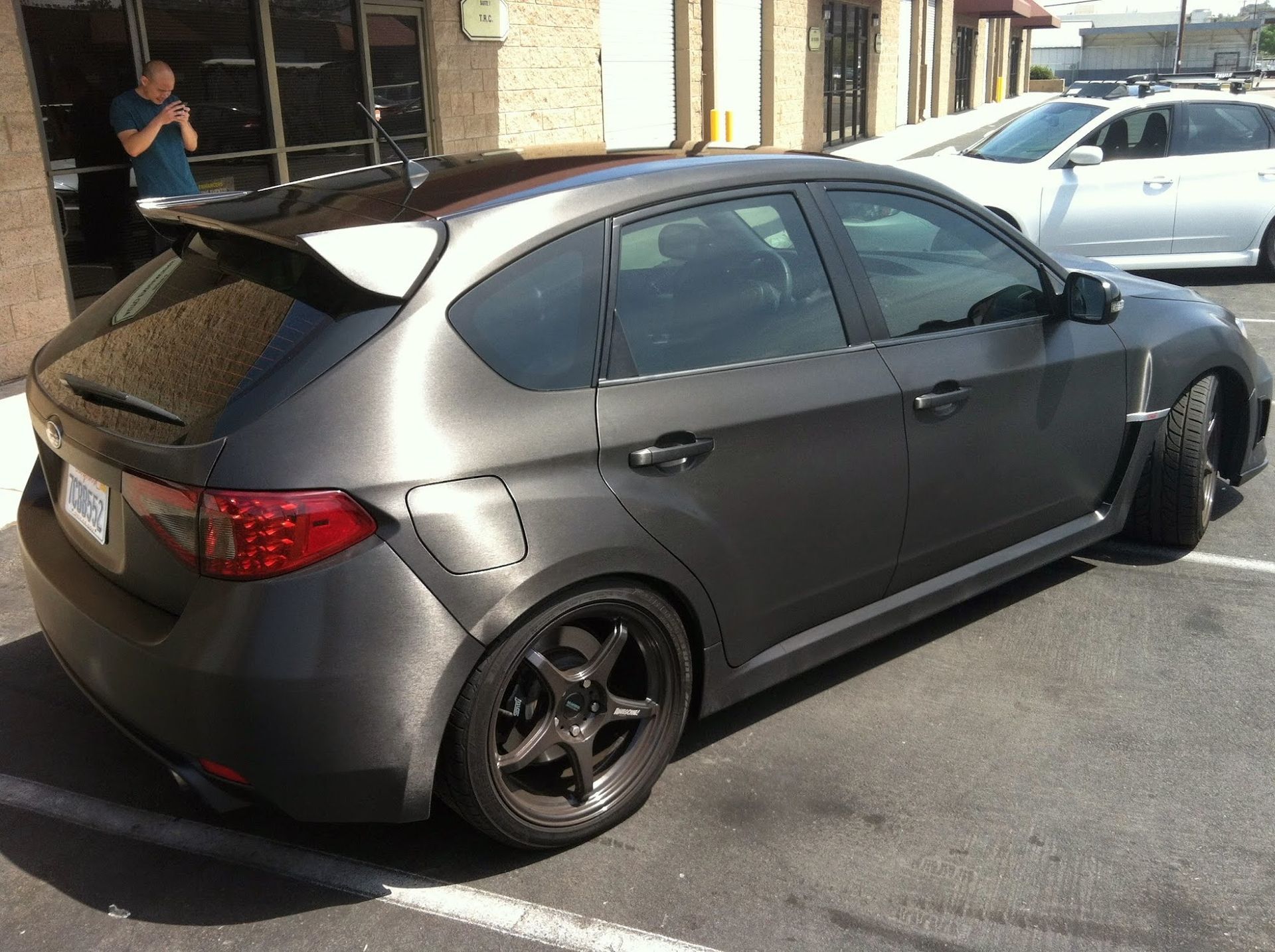 Dark gray Subaru hatchback with black wheels, parked outside.