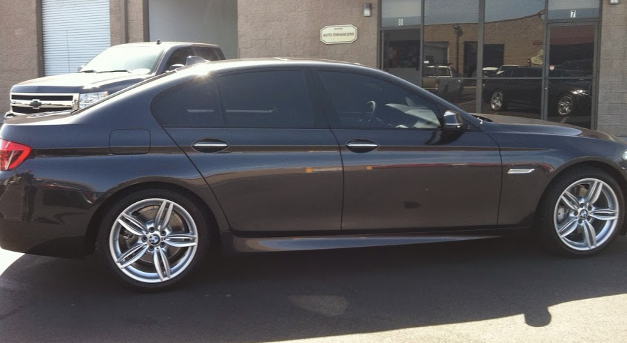 Dark gray BMW sedan with tinted windows parked outside a building.