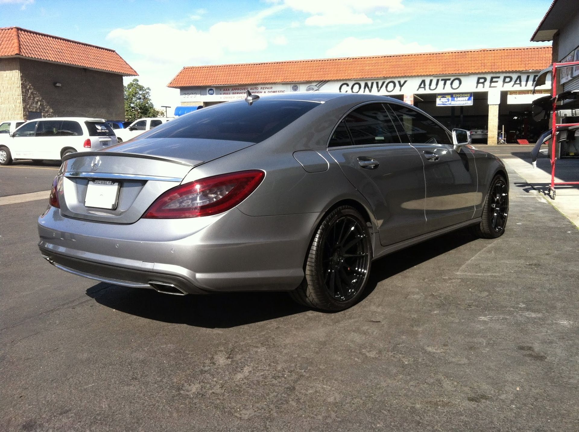 Gray Mercedes-Benz car with black rims parked outside Convoy Auto Repair under a sunny sky.