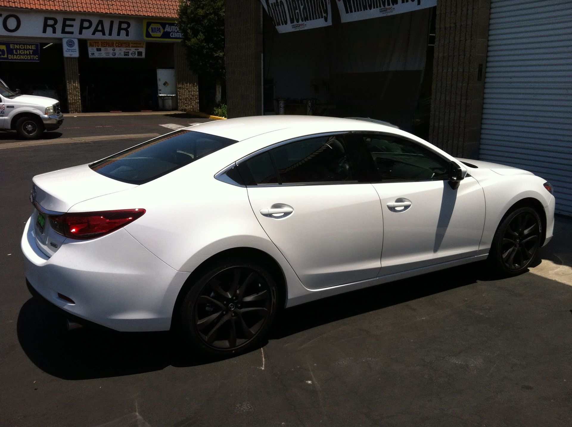 White sedan with black wheels parked in front of a garage.