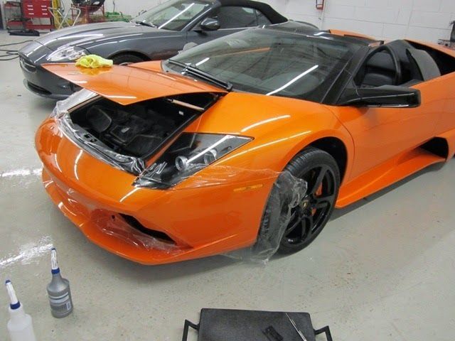 Orange Lamborghini with front wrapped in protective film in a garage.