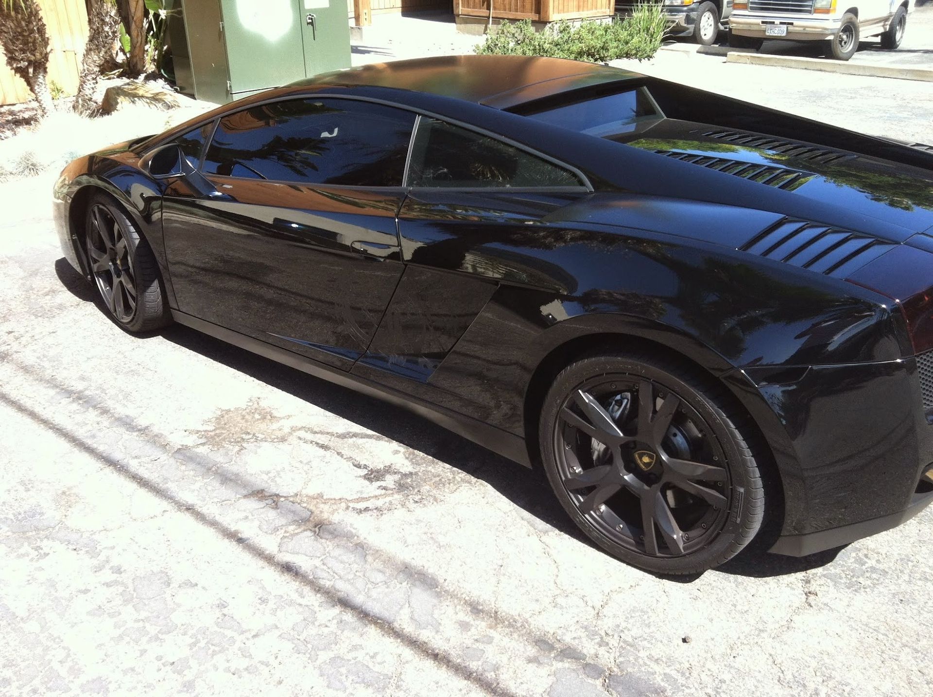 Black Lamborghini sports car parked on pavement.