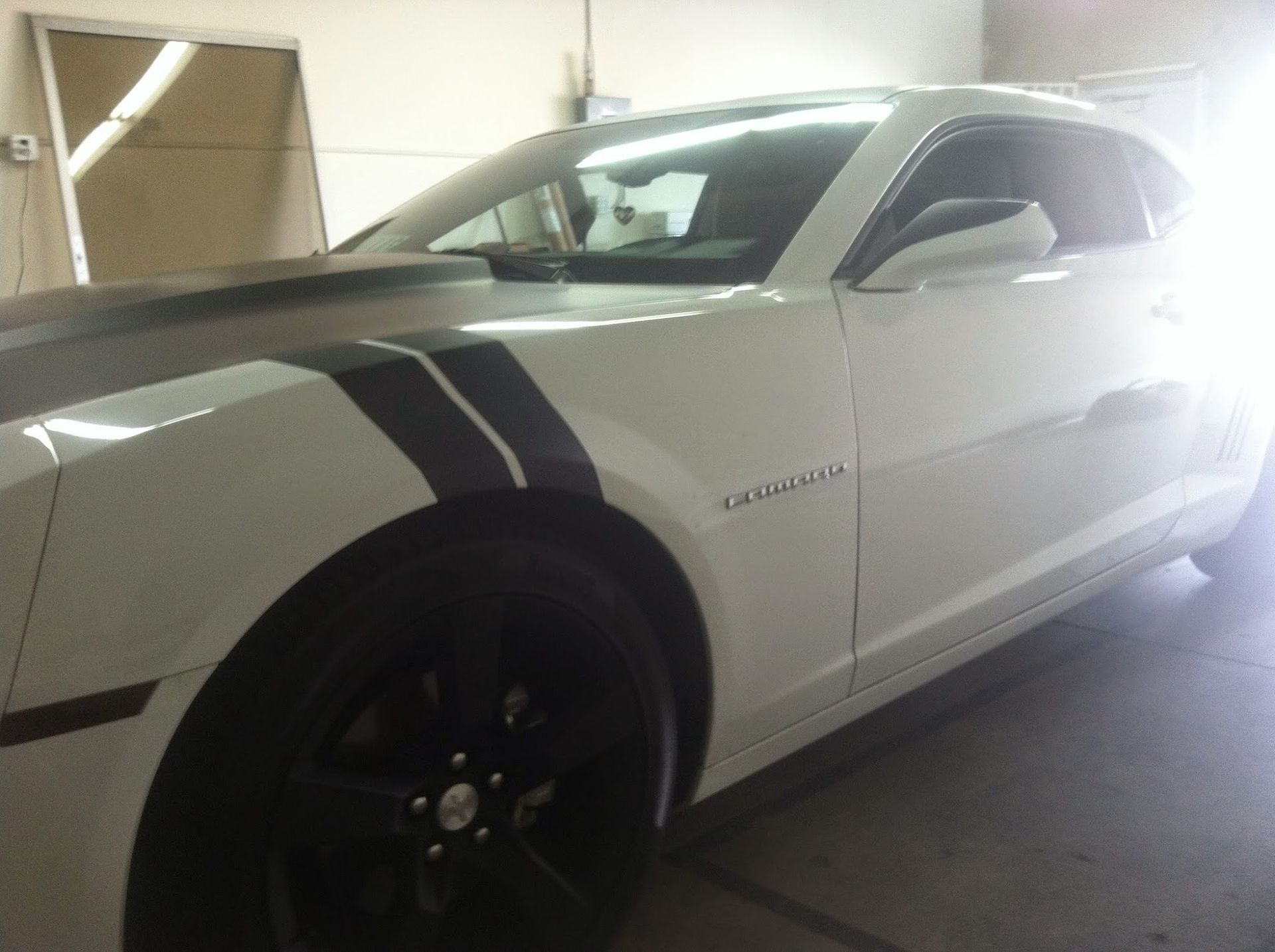 White sports car with black stripes, parked indoors.
