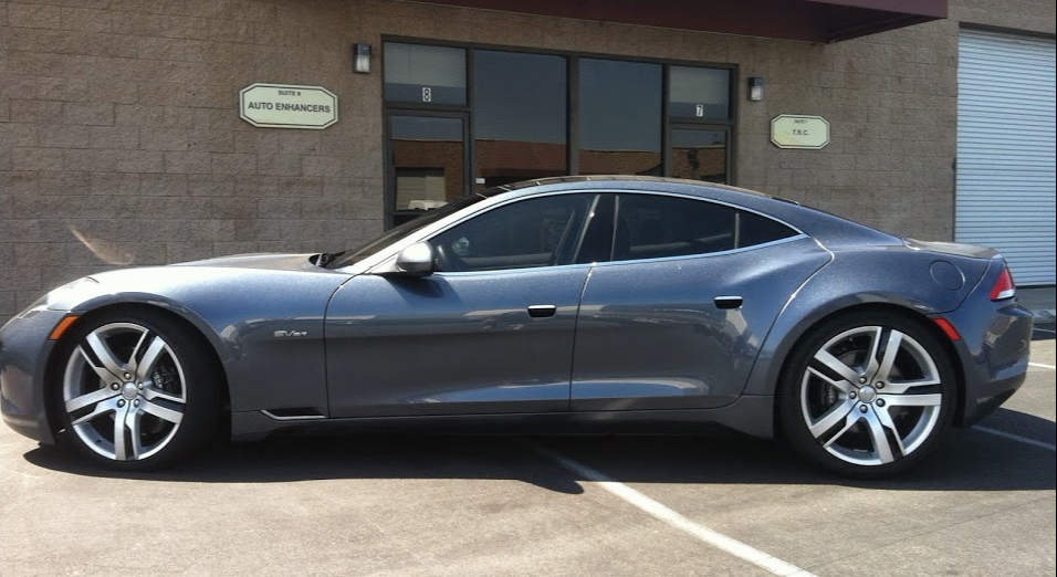Gray Fisker Karma car parked outside a building with tinted windows.