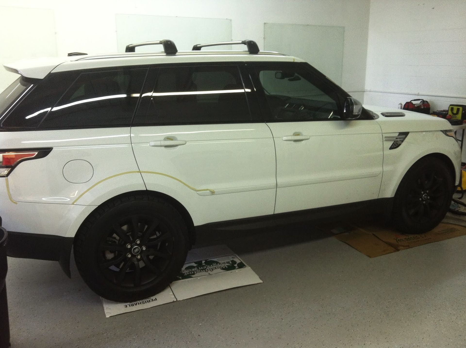 White Range Rover with black wheels and tinted windows, parked in a garage.