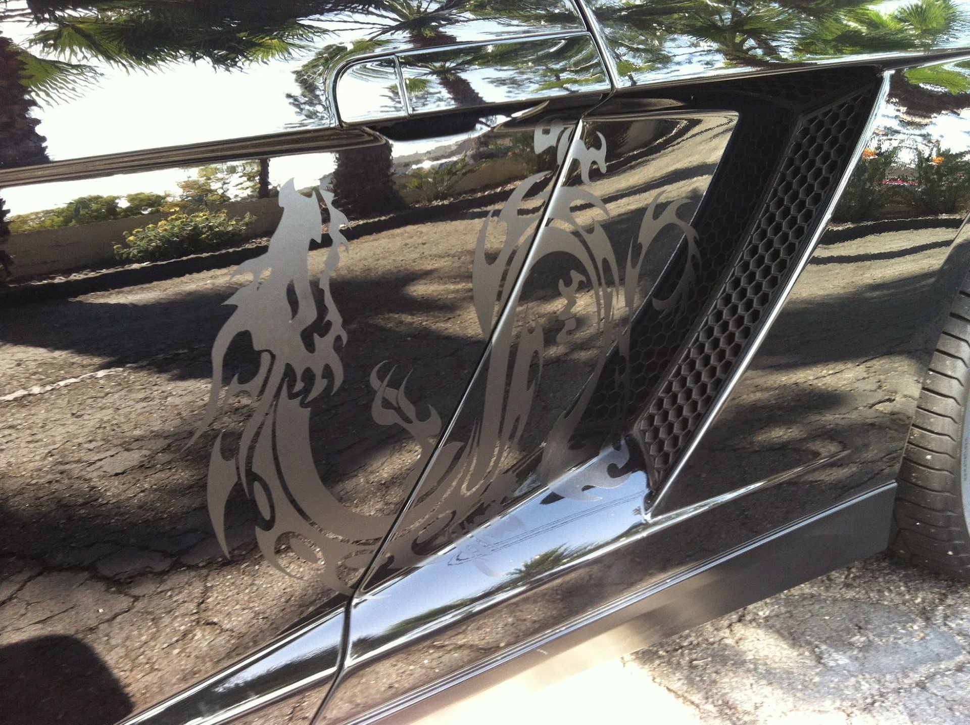 Black sports car with silver dragon decal on the side vent.