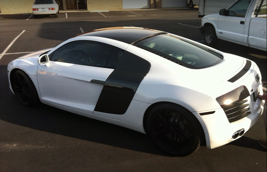 White Audi R8 sports car with black accents parked outdoors.