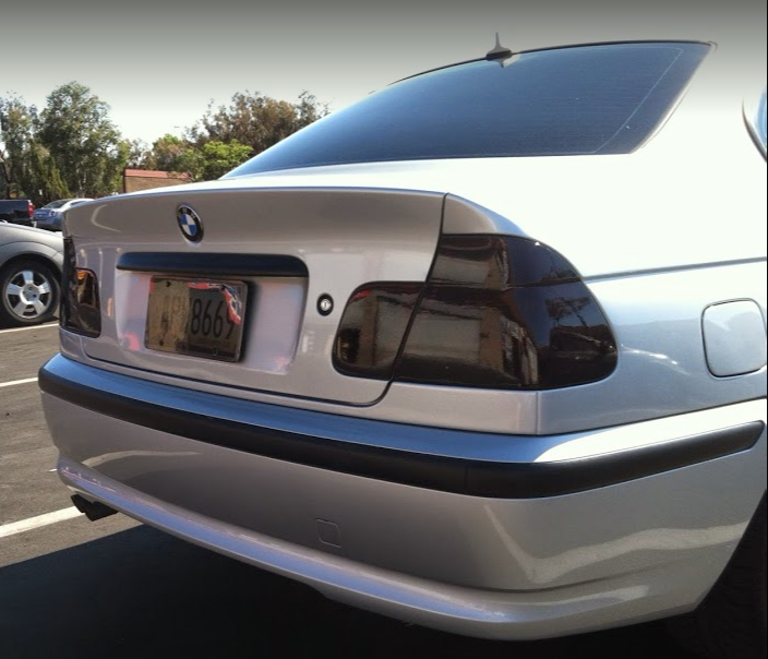 Silver BMW sedan with tinted taillights in a parking lot.