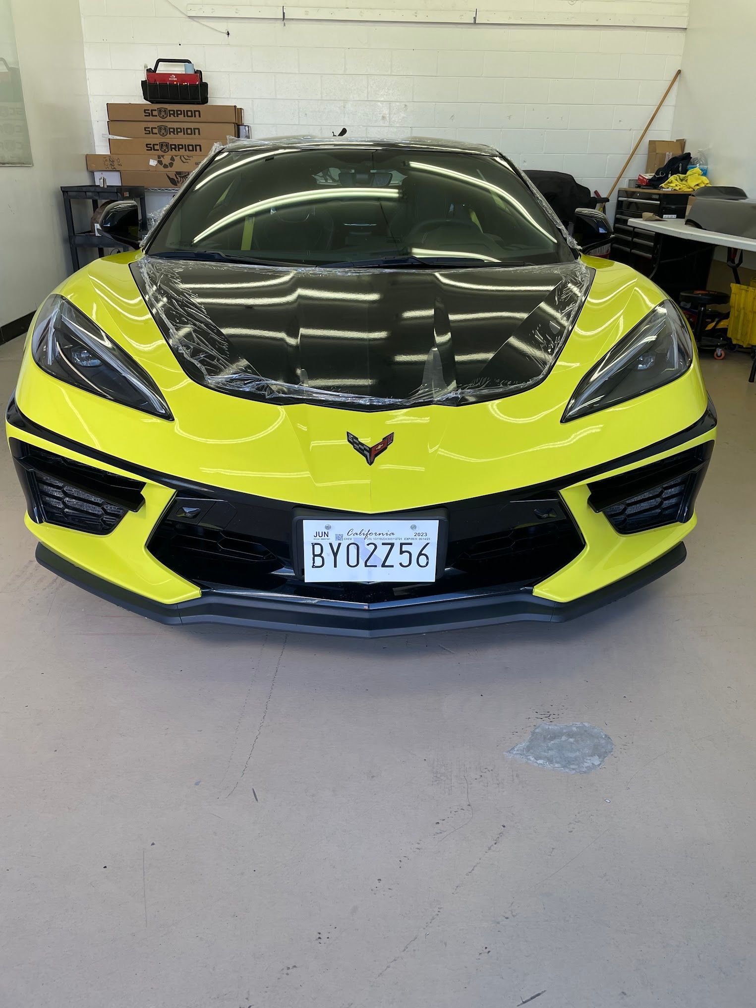 Yellow and black sports car with California license plate, parked in a garage.