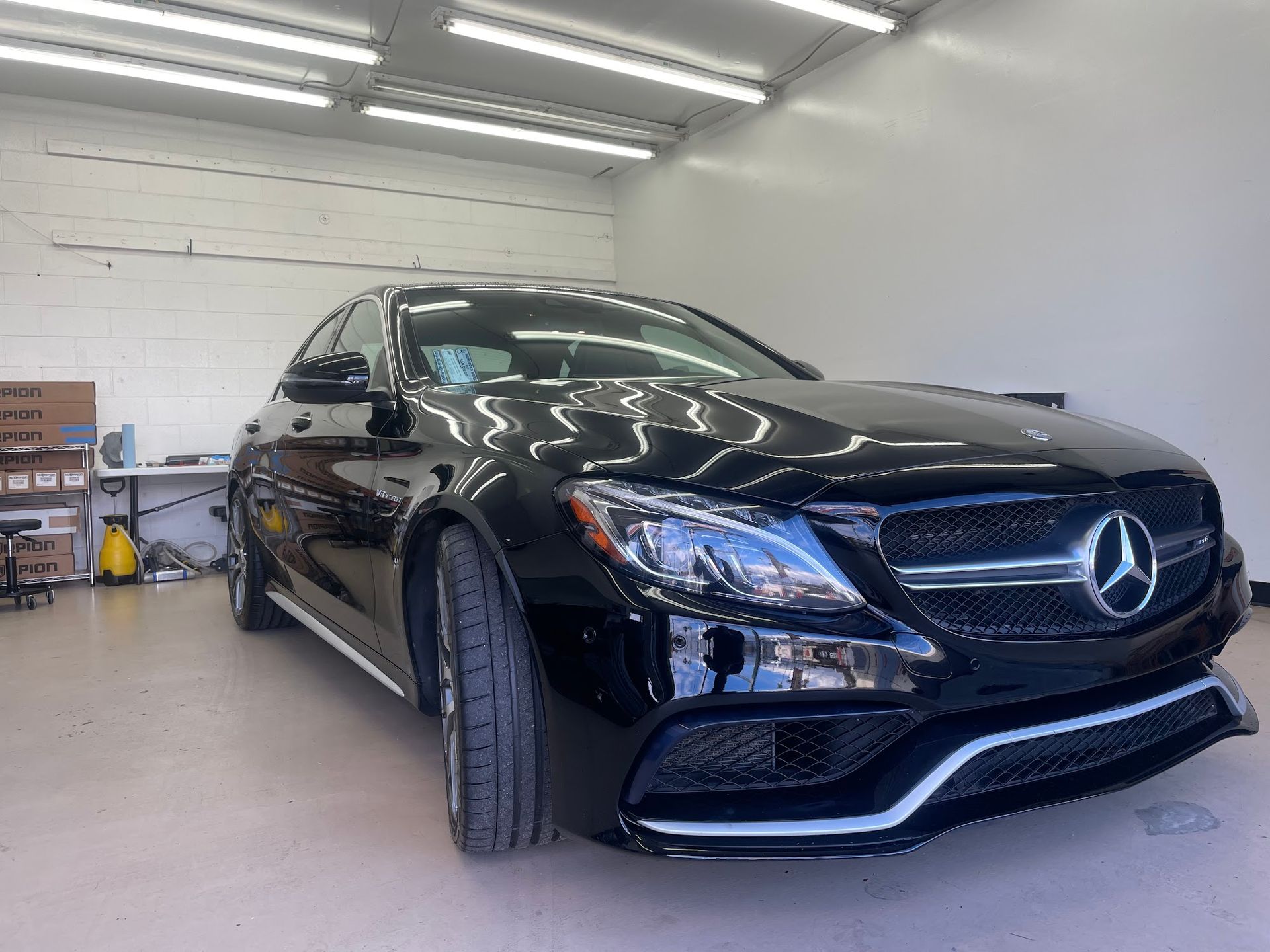 Black Mercedes-Benz car in a garage, shiny exterior.