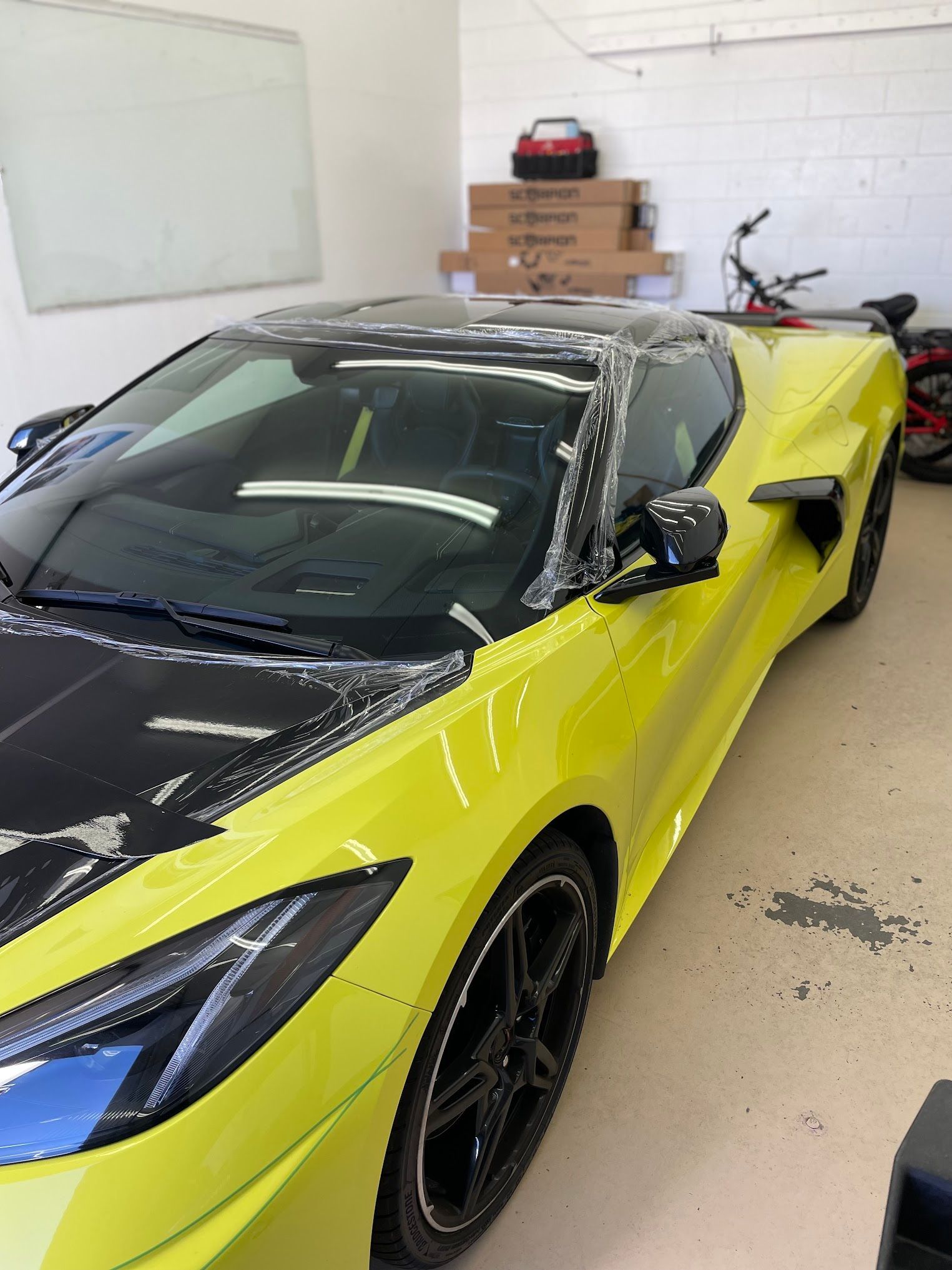 Yellow sports car with black accents being worked on inside a garage.