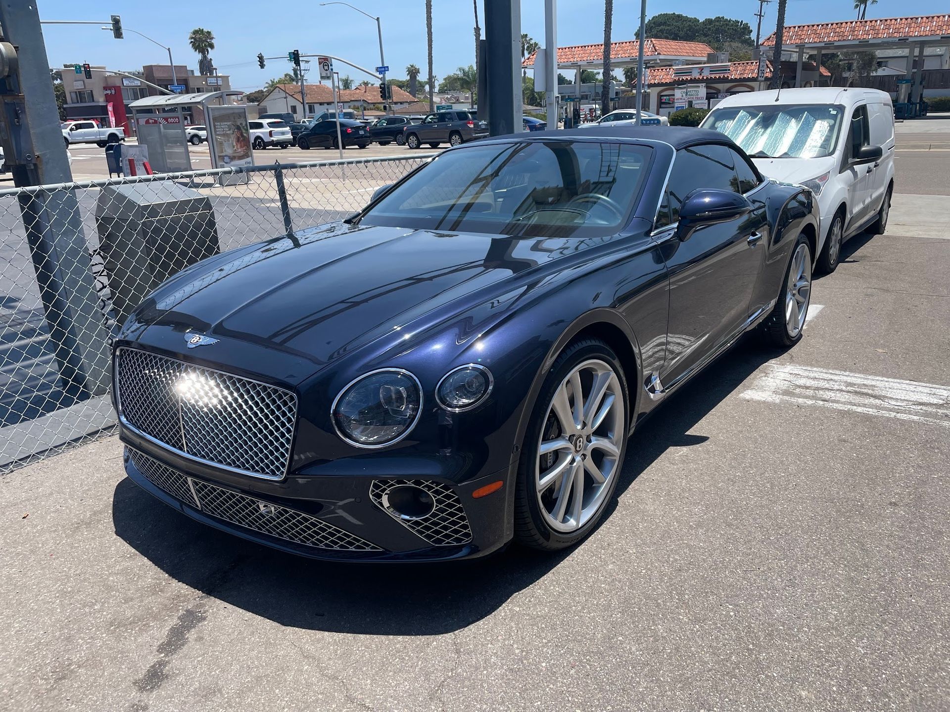 Blue Bentley convertible parked outdoors in front of a business.