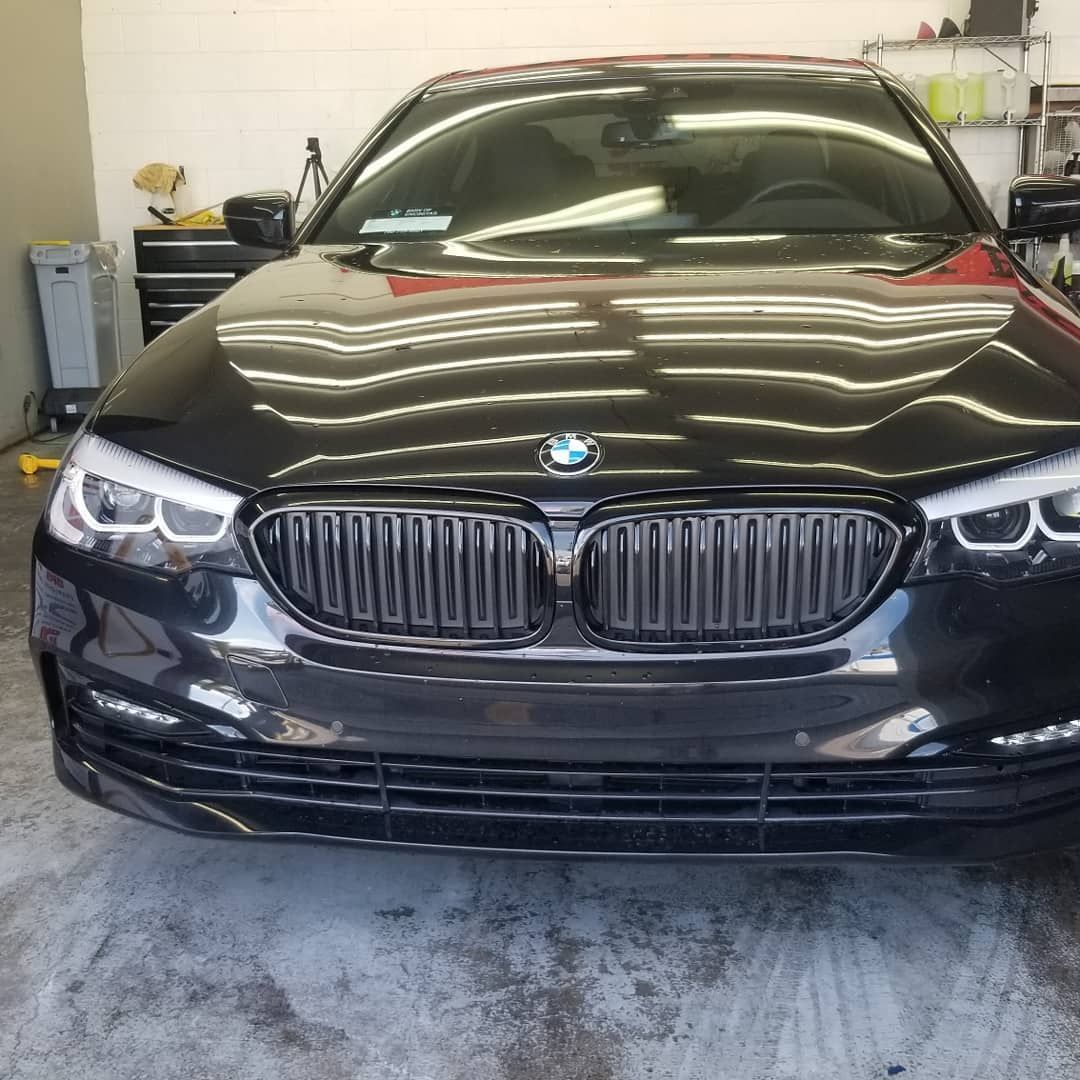 Black BMW sedan parked indoors, with reflective ceiling lights.