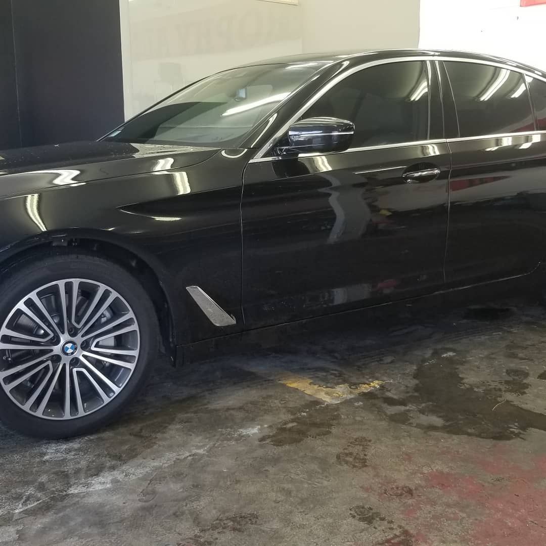 Black BMW sedan parked in a garage, side view showing the wheel and tinted windows.